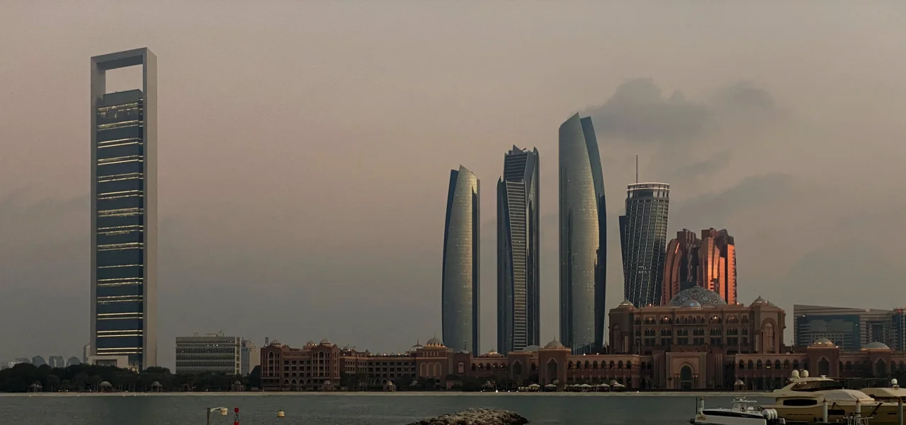 Abu Dhabi skyline at dusk seen from the water, with the Etihad Towers and the Emirates Palace
