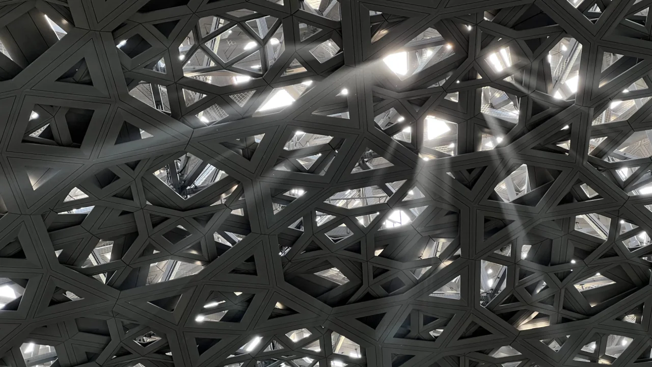 The latticed dome of the Louvre Abu Dhabi seen from below, light falling through its openings