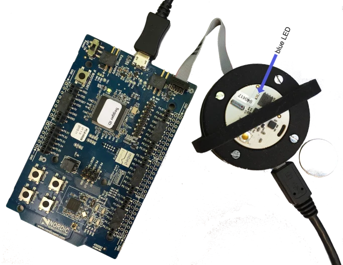An OpenBeacon tag placed on the spring contacts inside the round frame of the 3D-printed tag programmer