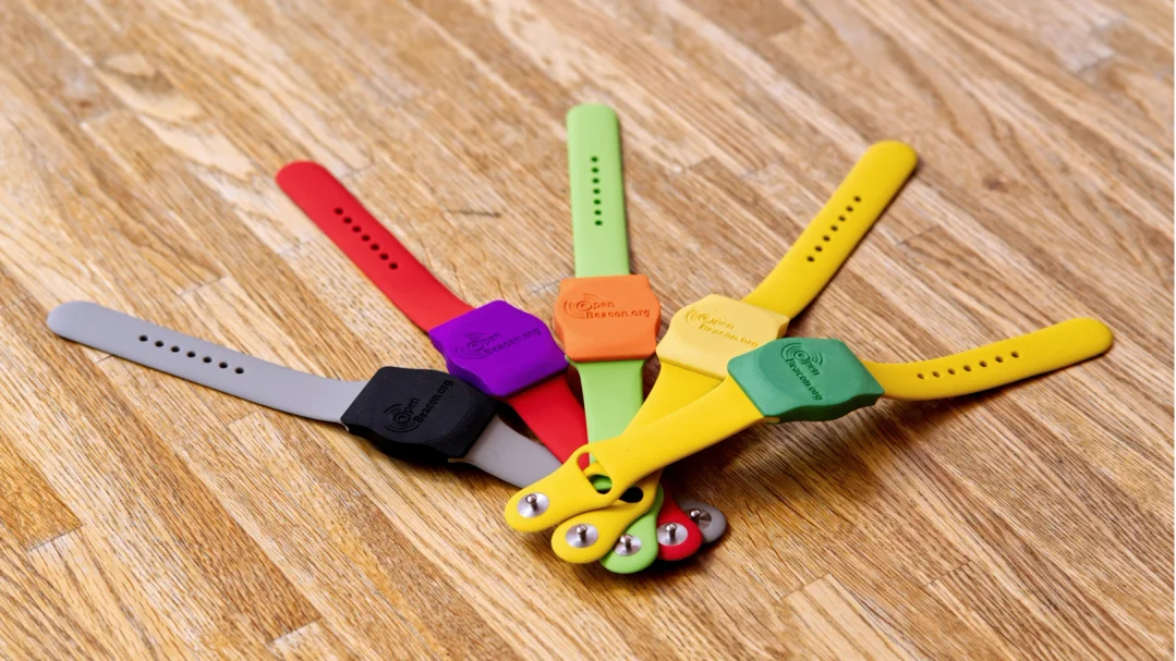 Colourful OpenBeacon wristbands fanned out on a wooden table