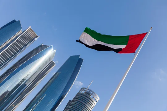 Flag of the United Arab Emirates flying in front of the Etihad Towers in Abu Dhabi